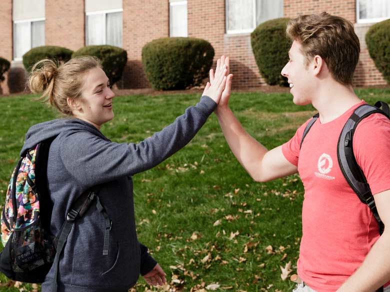 Two students high fiving.